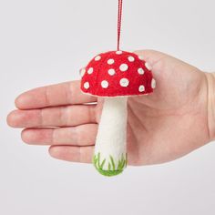 a hand holding a red and white mushroom ornament