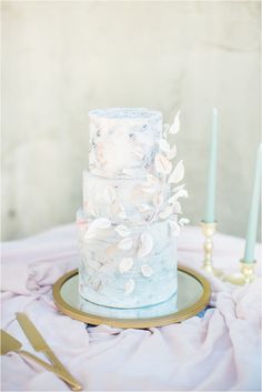 a three tiered cake sitting on top of a table next to two blue candles