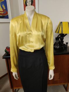 This is the second Peter Metchev label blouse that I'm listing. This one is a bright golden yellow polyester, soft and draping, with shoulder pads, long sleeves and a cuff, pleats at the shoulders and a button front. The condition is good except for a section on upper sleeve ( see photo ) Measurements are Shoulder to shoulder 42cm Bust 108cm Sleeves shoulder to cuff 60cm Length shoulder to hem 65cm Classic Gold Formal Blouse, Classic Gold Blouse For Workwear, Elegant Yellow Tops For Fall, Fitted Gold Top For Workwear, Fitted Gold Tops For Work, Formal Pleated Long Sleeve Blouse, Formal Long Sleeve Pleated Blouse, Classic Fitted Gold Blouse, Fitted Pleated Blouse For Office