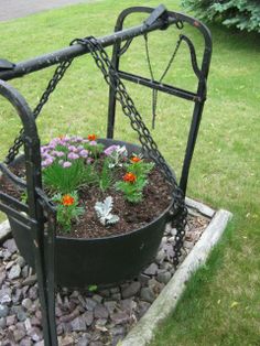 a metal planter filled with flowers on top of a bed of rocks and gravel