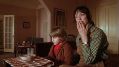 a woman sitting next to a child at a table with a glass of milk in front of her