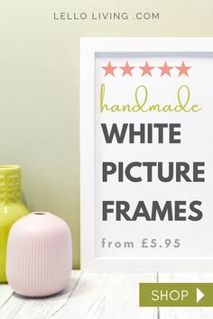 a white picture frame sitting on top of a table next to a vase and potted plant