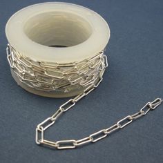 a spool of silver chain sitting on top of a blue table next to a roll of tape