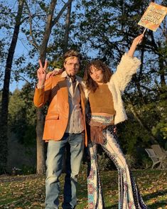 a man and woman posing for a photo in front of trees with their hands up