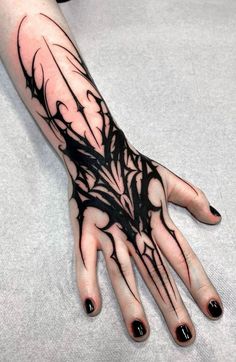 a woman's hand with black ink on it and some branches in the middle