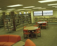 an empty library with tables and orange chairs