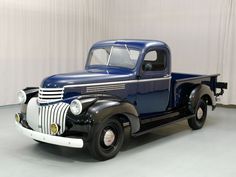 an old blue truck parked in a garage