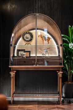 a desk with a clock on it in front of a potted plant