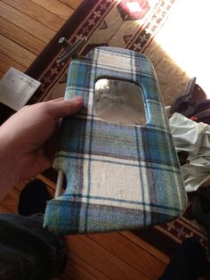 someone is holding their cell phone up to the camera lens case that has been made out of plaid fabric