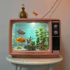 an old tv with fish in it sitting on a small table next to a wall