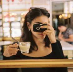 a woman taking a photo with her cell phone while sitting at a table in a restaurant