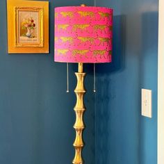 a pink and gold lamp in front of a blue wall