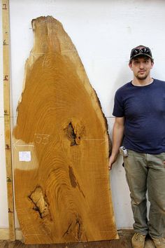 a man standing next to a large piece of wood that has been cut in half