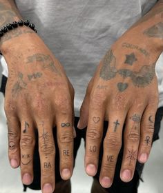 two hands with tattoos on them and one has an arrow, cross, heart, and other symbols