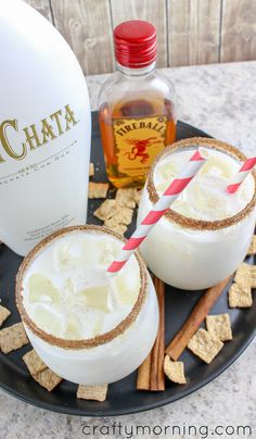 two cocktails on a black plate with cinnamon sticks