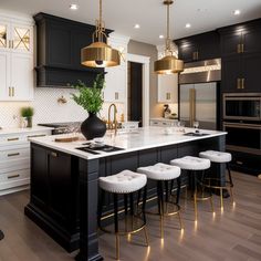 a kitchen with black cabinets, white countertops and bar stools in the center