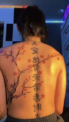 the back of a woman's body with chinese writing on it and flowers painted on her back