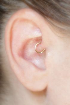 a close up of a person's ear with a gold nose ring