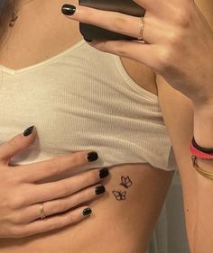 two women with tattoos on their stomachs and one has a phone in her hand