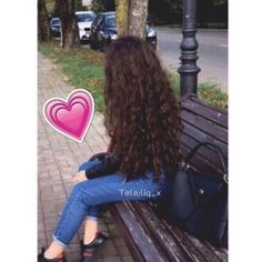 a woman sitting on top of a wooden bench