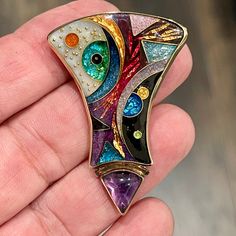 This stunning, vibrant pendant/brooch pin is circa 80s set in sterling silver with 14kt and 22kt accents and features a cabochon cut triangle amethyst gemstone made by Alexa & Peter Smarsh in Key Largo, Florida.    This pendant is signed by the artist and titled "Abstract Division".  This artist uses vibrant enamel colors with gold and silver foils and has breathtaking colors saturating the jewelry piece.  The triangle cabochon cut amethyst is bezel set and measures 11x8.87mm.  20.0 grams weight Multicolor Cabochon Brooches For Collectors, Unique Yellow Gold Enamel Brooch, Unique Multicolor Cabochon Brooches, Gold Multi-stone Enamel Jewelry, Artisan Collectible Jewelry Brooch, Unique Handmade Gold Enamel Pin, Unique Gold Brooch With Cabochon, Unique Gold Brooches With Cabochon, Artistic Formal Brooch Jewelry