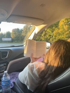 a woman reading a book in the back seat of a car