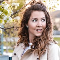 a woman in a trench coat standing under a tree