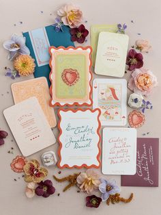 the wedding stationery is laid out on top of each other with flowers and cards