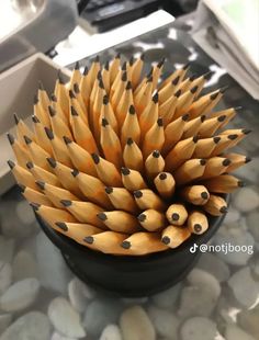 a black bowl filled with yellow pencils sitting on top of a stone countertop