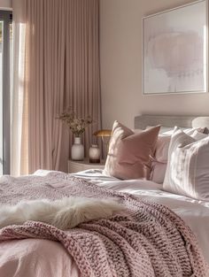 a bedroom with pink bedding, pillows and blankets on top of the bedspread