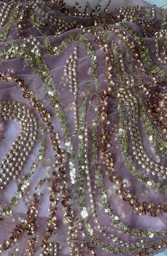 a purple and gold beaded mesh fabric with beads on the bottom, along with other sequins