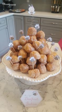 a plate full of doughnut holes on a table with honeybees in the background