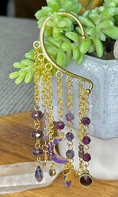 No piercing required with this beautiful beaded celestial ear cuff. Adorned with super flashy purple crystal beads. sold as a single Gold Bohemian Ear Cuff With Ear Wire, Bohemian Gold Ear Cuff For Festivals, Bohemian Adjustable Single Ear Cuff, Adjustable Bohemian Single Ear Cuff, Bohemian Gold Ear Climbers As Gift, Bohemian Gold Dangle Ear Cuff, Gold Bohemian Dangle Ear Cuff, Festival Dangle Ear Cuff For Pierced Ears, Handmade Dangle Ear Cuff For Festivals