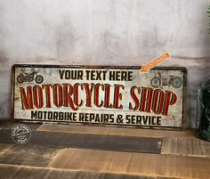 a motorcycle shop sign sitting on top of a wooden table next to a green vase