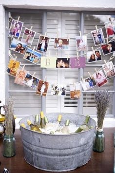 a bucket filled with wine bottles and pictures hanging from clothes pins