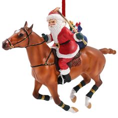 a santa clause riding on the back of a brown horse with a christmas tree ornament hanging from it's side