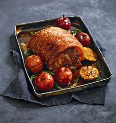 a roasting pan filled with meat, apples and other food on top of a table