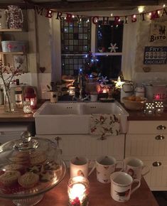 a kitchen counter topped with lots of cookies and tea cups next to a sink filled with candles