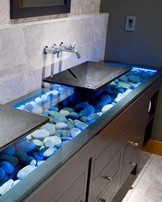 two sinks with blue rocks under them in a bathroom