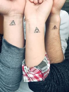 two people with matching tattoos on their arms holding each other's hands and looking at the camera