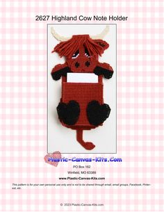 a red and black cow with horns on it's head is hanging from a wall