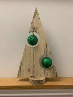 two green and white ornaments are hanging on a wooden shelf next to a fireplace mantel