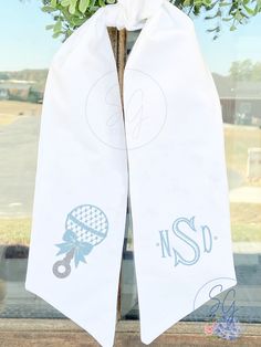 two white towels hanging on a window sill with flowers in the front and behind them