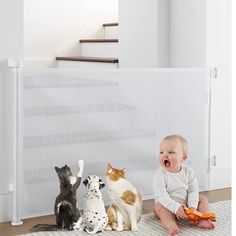 a baby sitting on the floor next to three cats