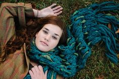 a woman laying on the ground wearing a scarf