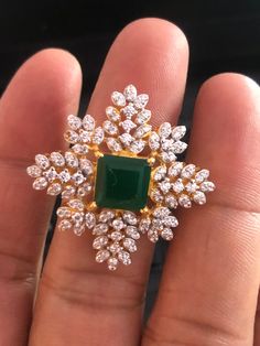 a woman's hand holding an emerald and diamond ring