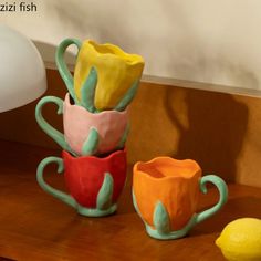 three ceramic cups sitting next to each other on a wooden table with two lemons