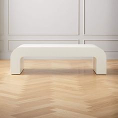 a white coffee table sitting on top of a hard wood floor next to a wall