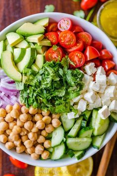 a salad with chickpeas, tomatoes, cucumber, lettuce and avocado