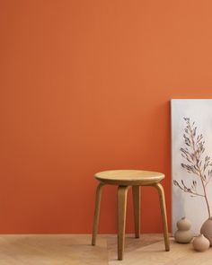 an orange wall with two vases and a small wooden stool in front of it